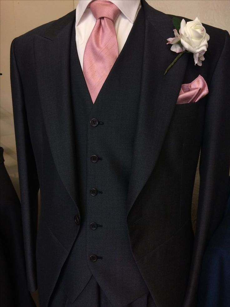 a black suit with pink tie and white flower