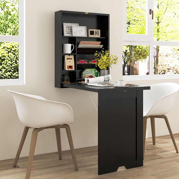 a desk with two chairs and a bookcase in front of a window on the wall