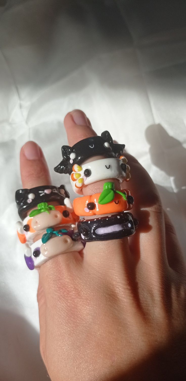 a person's hand holding three rings with cartoon characters on them, all in different colors