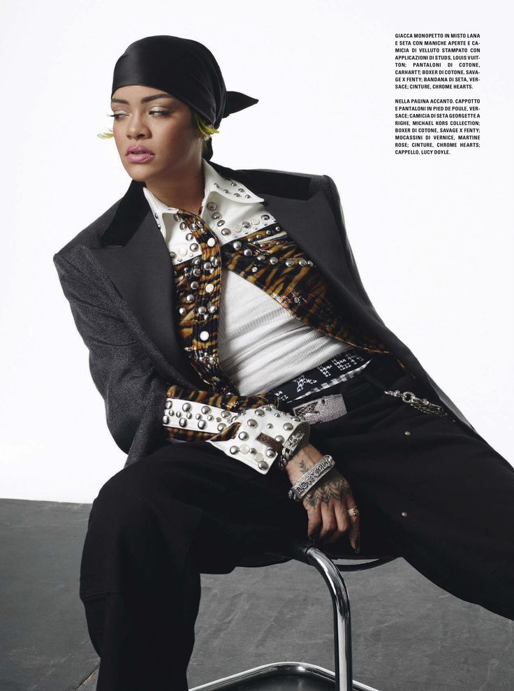 a woman sitting on top of a metal chair wearing a black and white shirt, tie and hat