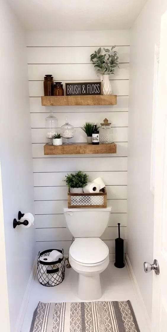 a white toilet sitting in a bathroom next to a wooden shelf filled with potted plants