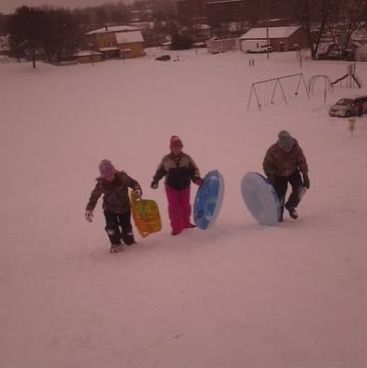 three people are walking in the snow with surfboards on their feet and one person is carrying two boards