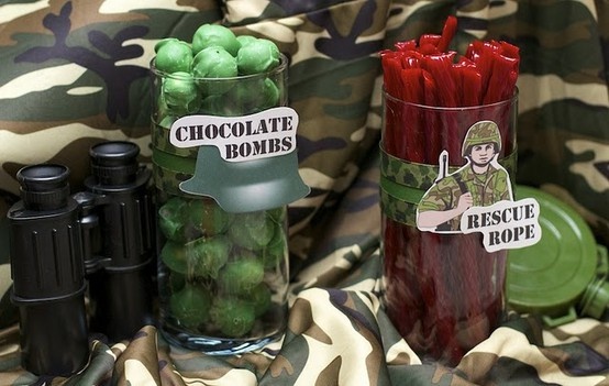 three jars filled with candy sitting on top of camouflage