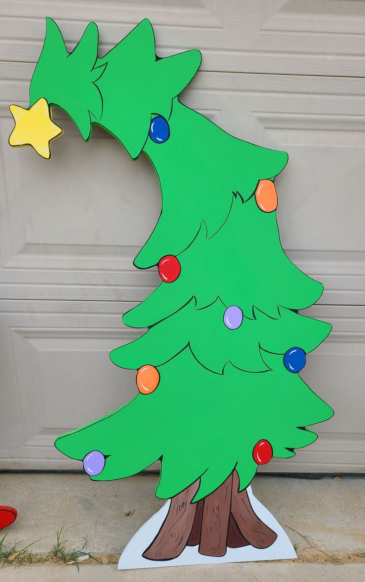 a cardboard christmas tree with lights on it sitting in front of a garage door next to a red fire hydrant