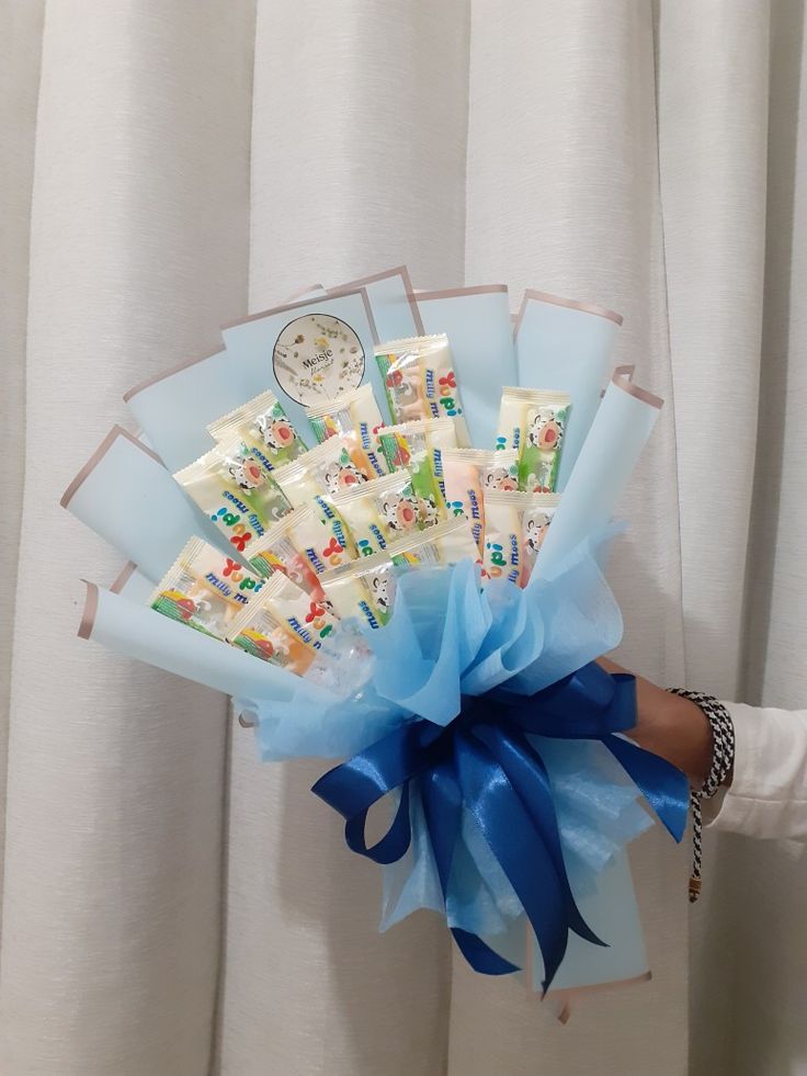 a person holding a bunch of cards in front of a white curtain with blue ribbon