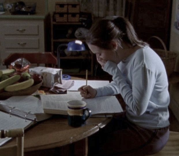 a woman sitting at a desk writing on a piece of paper