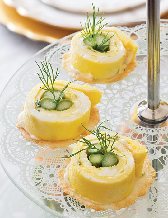 small pastries with cucumbers and herbs on a glass plate next to silverware