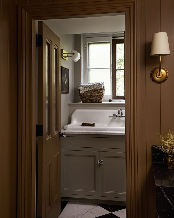 an open door leading to a bathroom with a sink and window in it's center