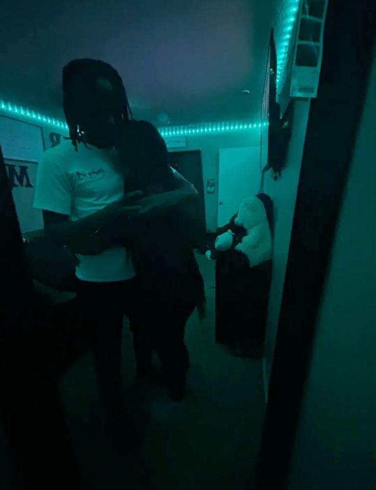 two people standing next to each other in a room with green lights on the walls