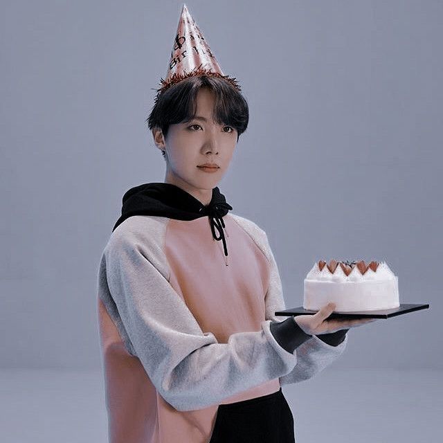 a woman in a party hat holding a cake