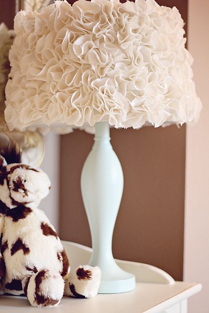 a stuffed animal sitting next to a lamp on top of a white table with a light shade