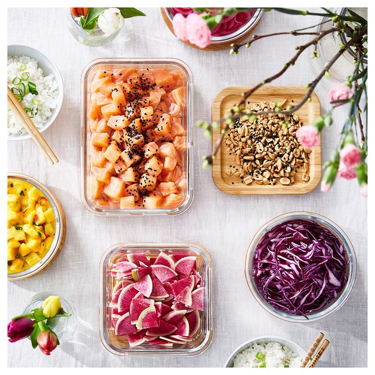 various bowls of food on a table with chopsticks and flowers in the background