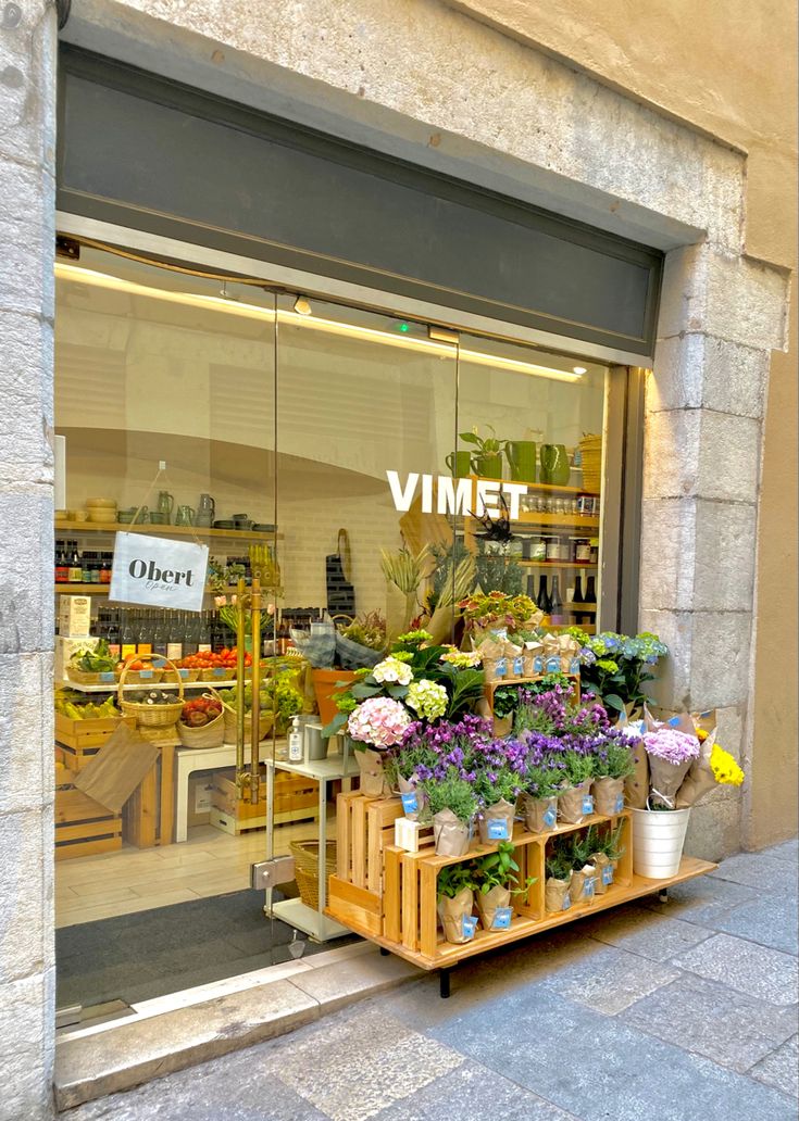 a store front with flowers and plants in the window