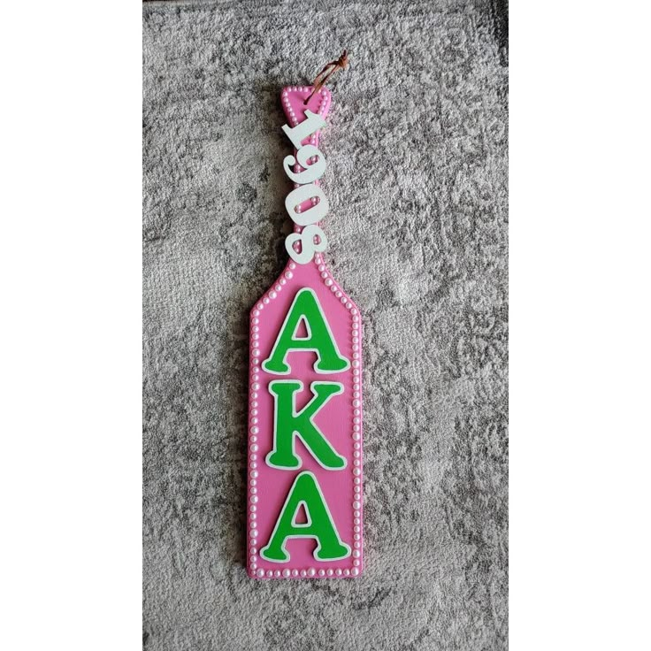 a pink and green keychain with the word aka on it's side