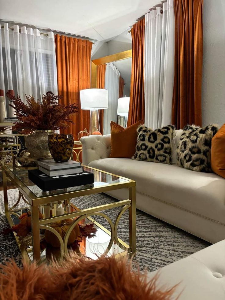 a living room filled with furniture and lots of orange drapes on the windowsill