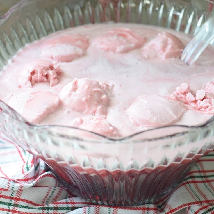 a dessert in a glass dish with pink icing and marshmallows on top