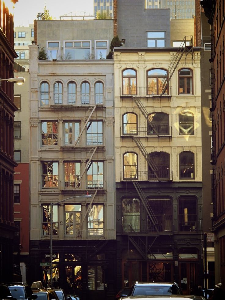 cars are driving down the street in front of tall buildings with balconies on them