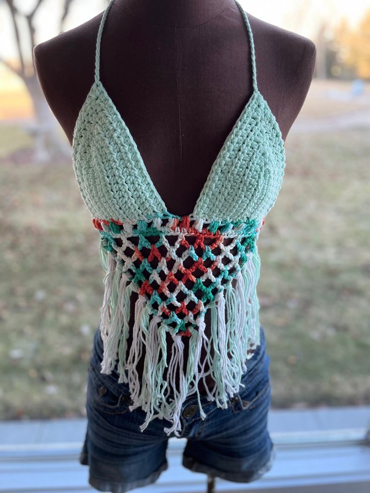 Beautifully handmade crochet bikini top. These look amazing paired with your favorite flannel or just with your favorite shorts and sandals! One size fits most.  The back and top tie so they are very adjustable. The cup size is universal depending on how much coverage you want. This style is very flattering on many different body styles. Color is teal/mint and multicolored orange/white. Can also be made in colors of your choice. Message the shop to create your own colors! Bohemian Green Crochet Beach Top, Bohemian Green Crochet Top For Beach, Multicolored Crochet Top, Multicolor Cotton Halter Top For Beach, Green Bohemian Halter Top For Beach Season, Crochet Triangle Halter Top For Beach Party, Handmade Triangle Top For Beach, Adjustable Bohemian Halter Top For Festivals, Green Crochet Top For Beach Season