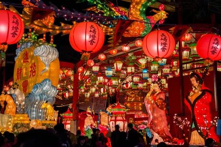 many lanterns are lit up at night with chinese characters on them and people standing around