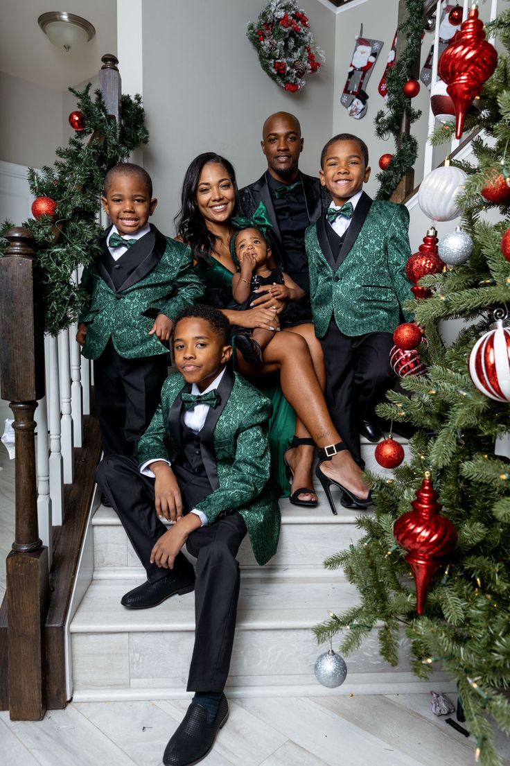 a group of people sitting on the steps in front of a christmas tree