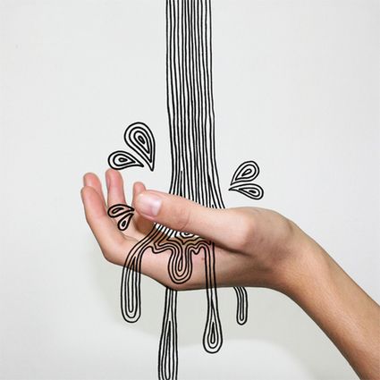 a person holding their hand up to an art piece with lines drawn on the wall