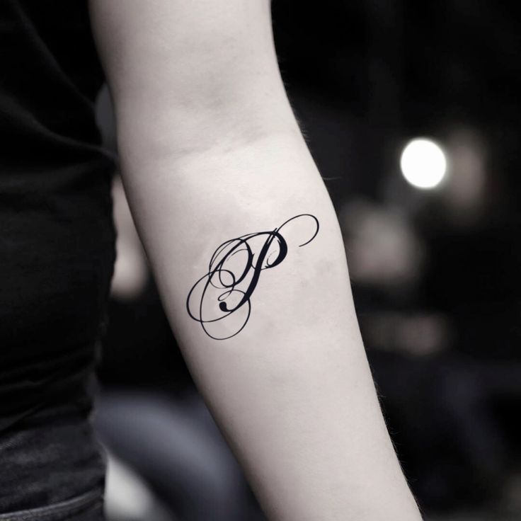 a woman's arm with a tattoo on it that has the letter p in cursive writing