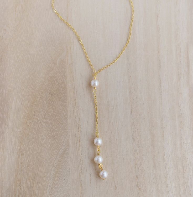 Pearls are believed to be a calming, centering gem that nourishes integrity, faith, and loyalty. They are also symbols of femininity, helping women connect with their inner goddess or feminine energy.This necklace features four white freshwater pearls dropping from a chain. Each pearl is semi-round with natural grooves, divots, and ridges on its surface. Chains are available in sterling silver or 14k gold filled. The pearl pendant hangs 3 inches from the chain.MATERIALSStone: Freshwater PearlMet Gold Spiritual Necklace With Pearl Drop, Spiritual Gold Necklace With Pearl Drop, Spiritual Gold Necklaces With Pearl Drop, Gold Spiritual Pearl Necklace, Spiritual Gold Pearl Drop Necklace, Graceful Gold Pearl Necklace, Graceful Gold Pearl Chain Jewelry, Graceful Gold Jewelry With Pearl Charm, Helping Women