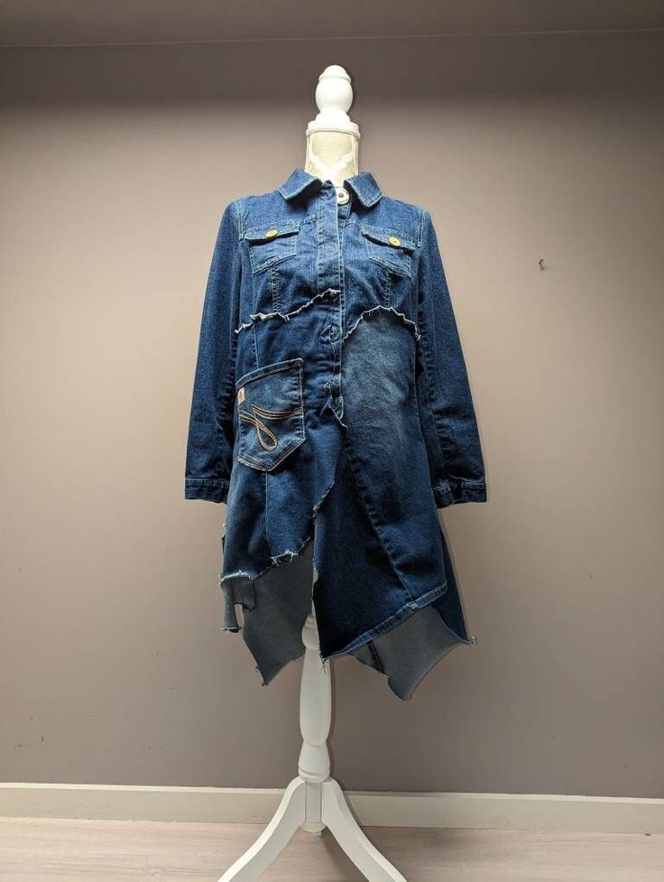 "Upcycled denim jacket with longer frayed patchwork detail. Bust measures 36\". Length varies from 27\" to 40\". Jagged hem. Arm length is 22\" from shoulder to cuff." Fall Patchwork Recycled Denim Jacket, Recycled Denim Long Sleeve Outerwear For Fall, Long Sleeve Recycled Denim Outerwear For Fall, Dark Wash Long Sleeve Denim Jacket With Patches, Dark Wash Denim Jacket With Patches, Distressed Recycled Denim Outerwear For Fall, Reworked Long Sleeve Denim Outerwear, Reworked Medium Wash Denim Jacket For Fall, Medium Wash Patchwork Denim Jacket