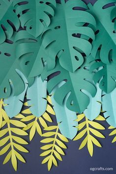 paper cut out of leaves with yellow and green accents on the bottom, against a dark blue background