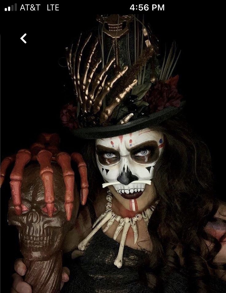 a woman in skeleton makeup holding up her hand with the fingers painted white and red