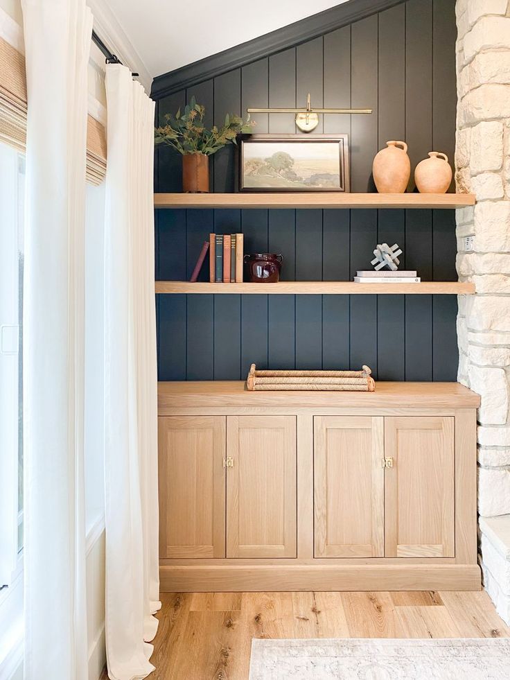 a book shelf with books and vases on it next to a window in a room