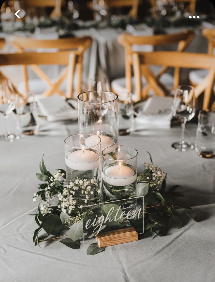 candles and greenery are placed on the centerpieces at this elegant wedding reception