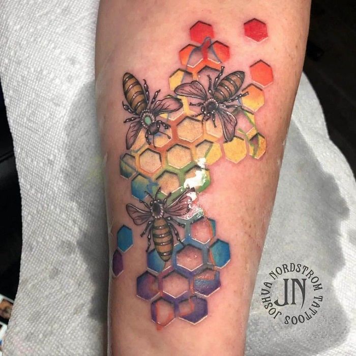 a tattoo with bees and honeycombs on the arm, which is colored in different colors