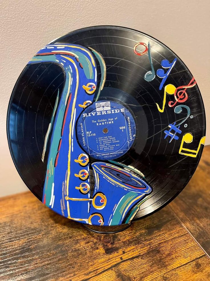 an old vinyl record with musical notes on it sitting on a wooden table in front of a white wall