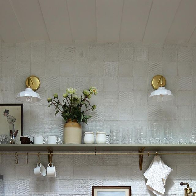 a kitchen with white walls and gold trimmings on the shelf above the sink