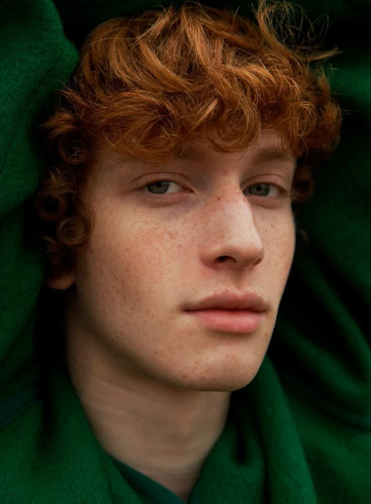 a young man with freckled red hair wearing a green scarf