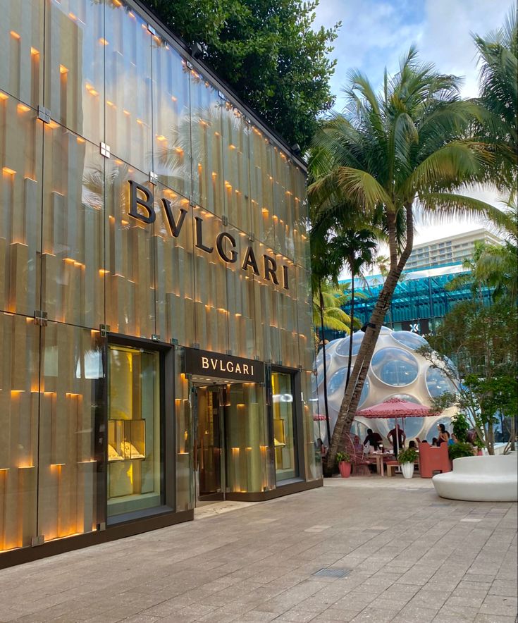 the entrance to bvlgari is lit up with lights and palm trees around it