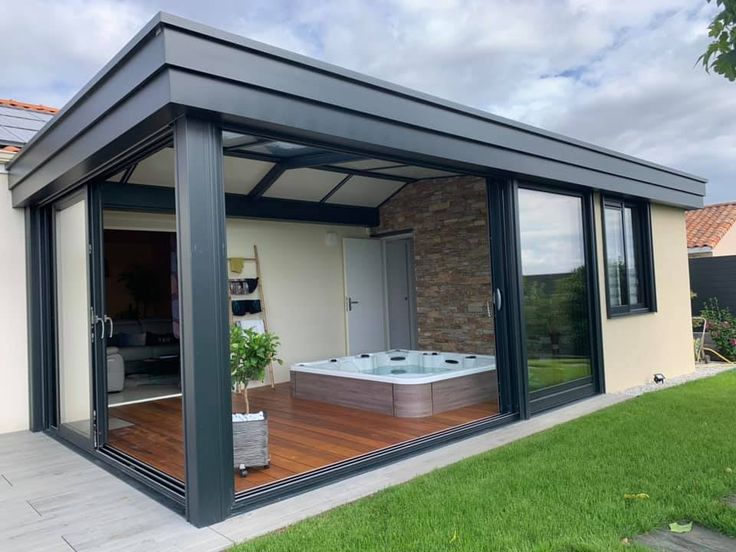 an outdoor jacuzzi tub in the middle of a backyard with sliding glass doors