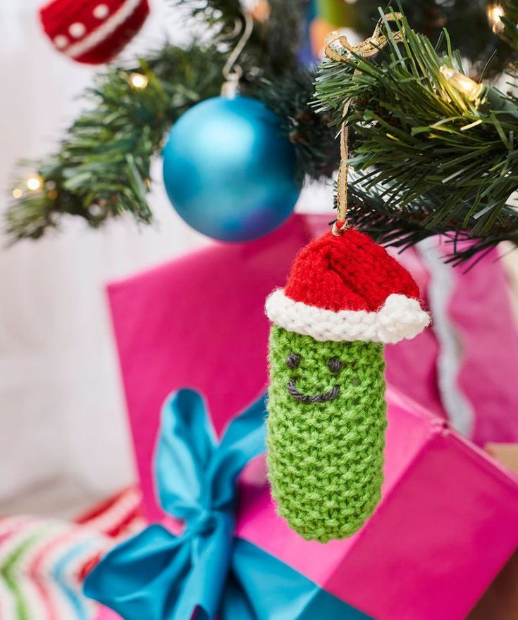 a christmas ornament hanging from a tree with presents under it and ornaments around it