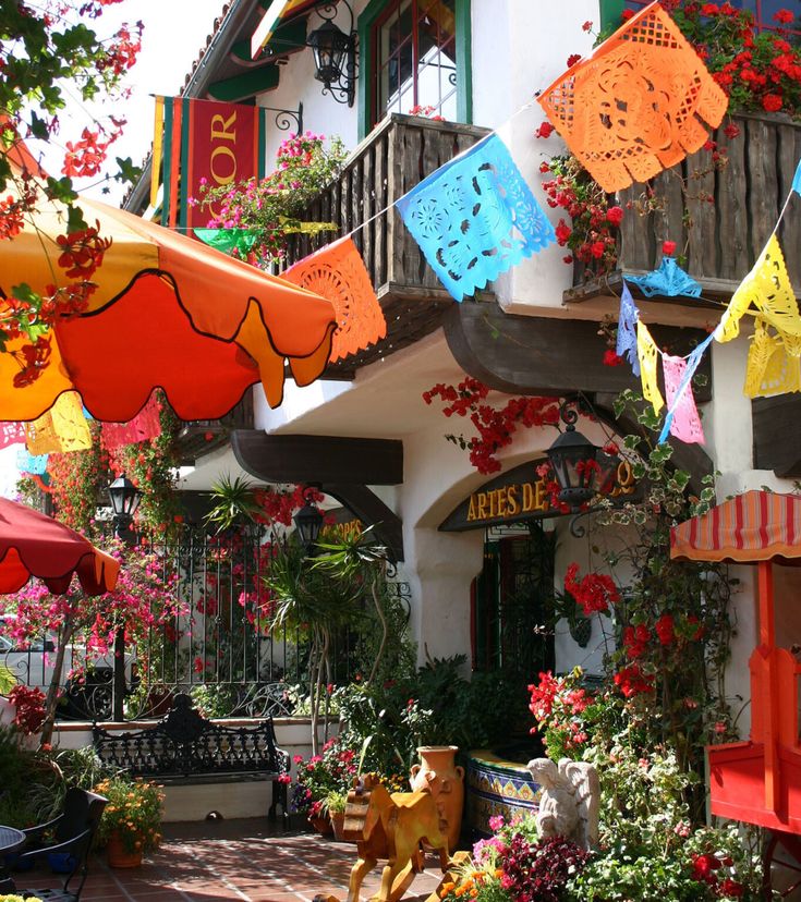 many colorful umbrellas are hanging from the side of a building with flowers on it