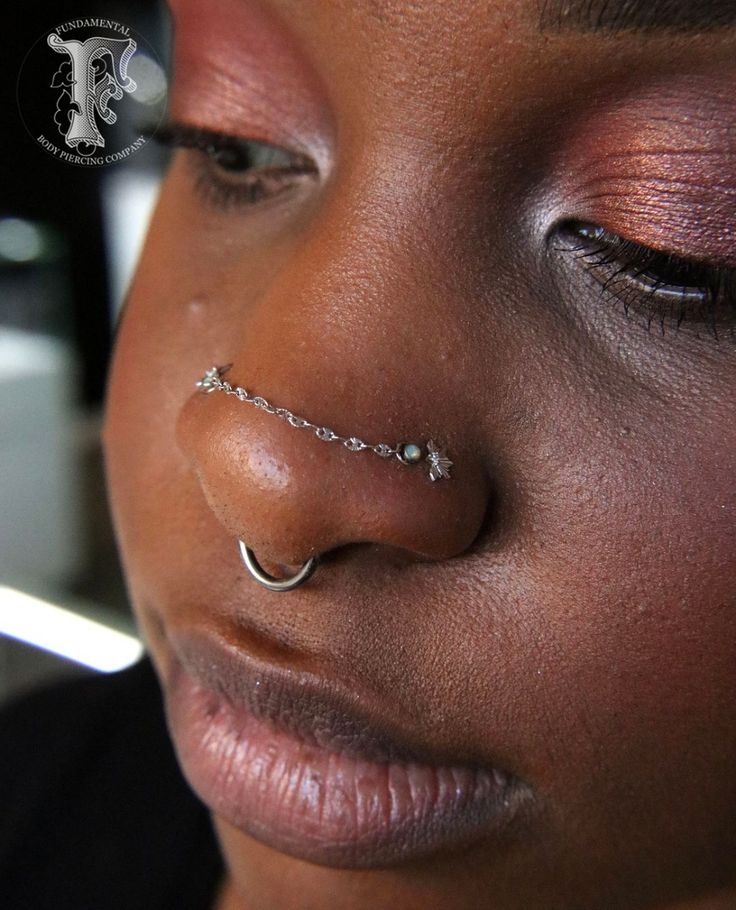 a close up of a person with piercings on their nose and nose rings in front of them