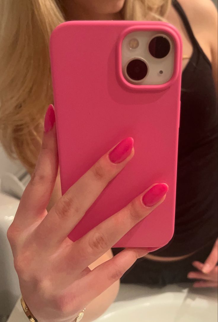 a woman holding up a pink phone case