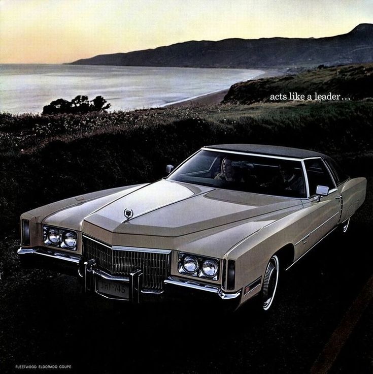 an old car is parked in front of the ocean