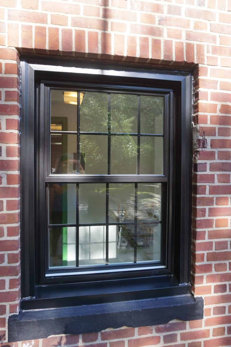 a brick wall with a black window frame and glass panes on the bottom half