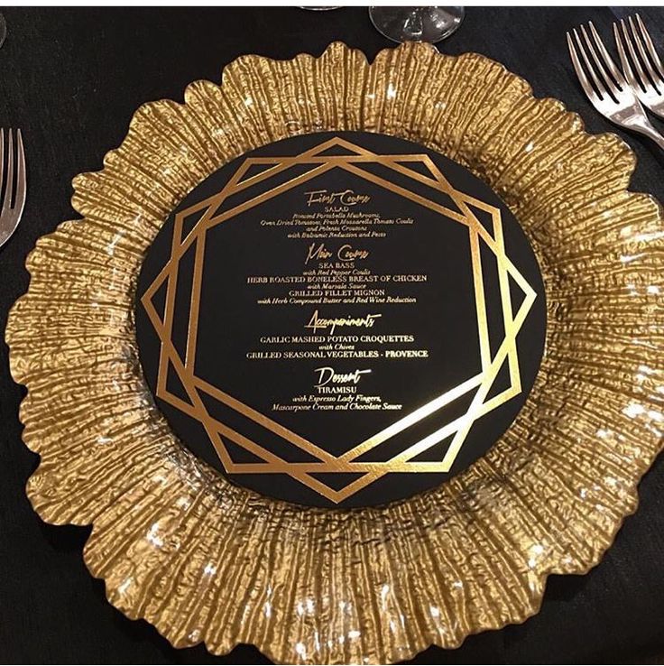 a black and gold dinner plate with silverware on the side, next to a knife and fork