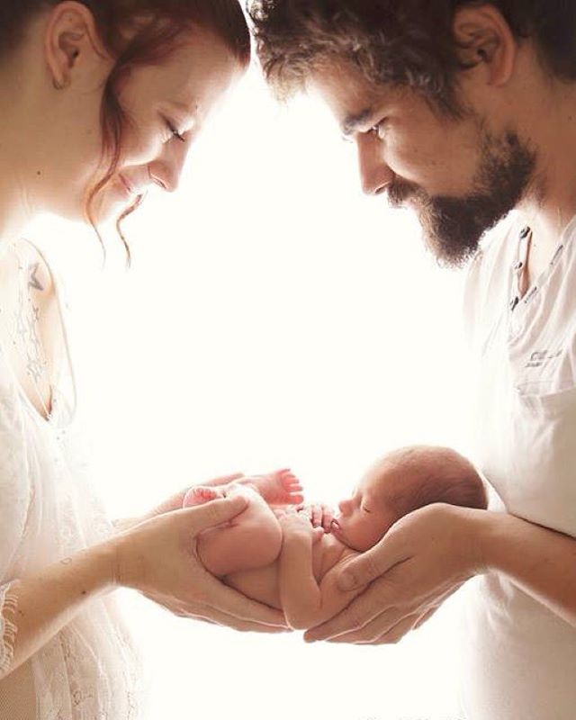 a man and woman holding a baby in their hands