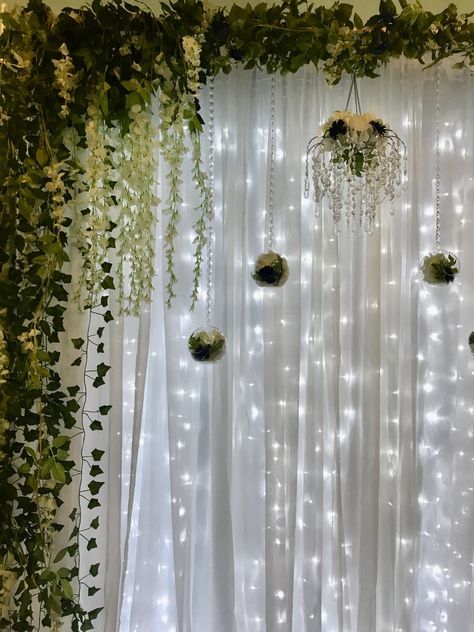 the curtain is decorated with greenery and lights