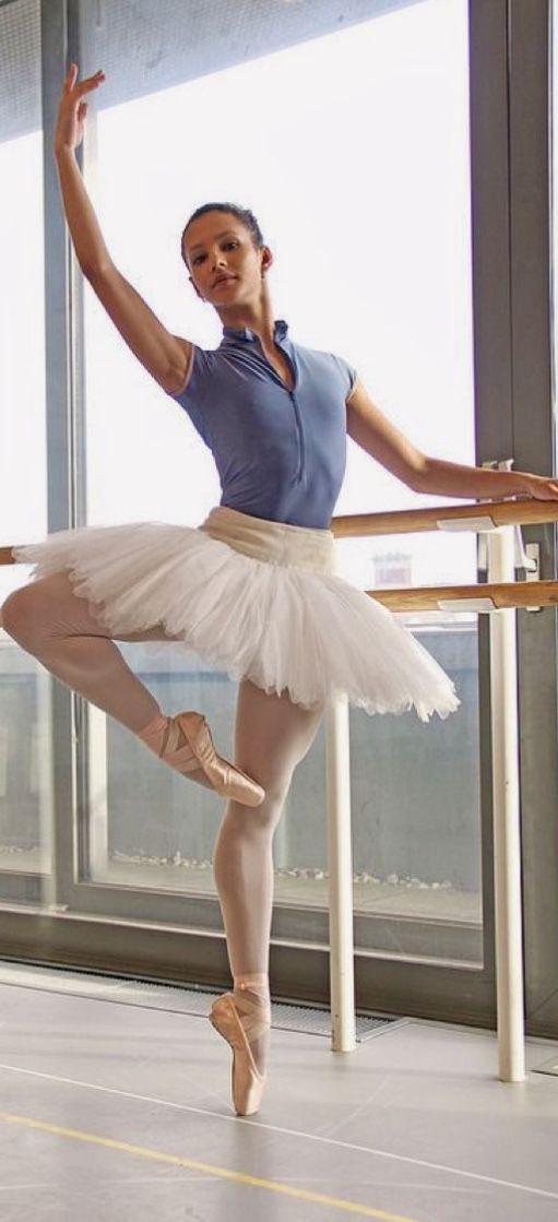 a ballerina is posing for the camera in front of a window with her arms stretched out