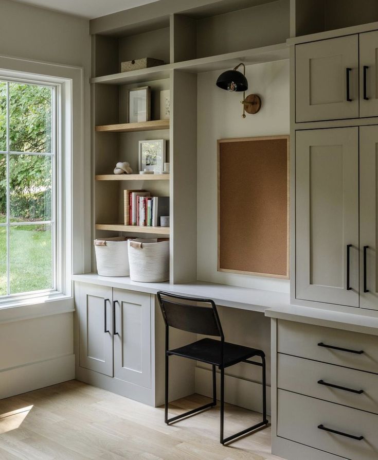 a chair sitting in front of a window on top of a wooden desk next to a book shelf