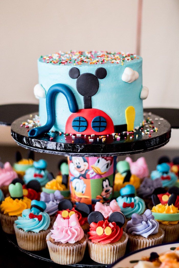 a mickey mouse cake and cupcakes on a table